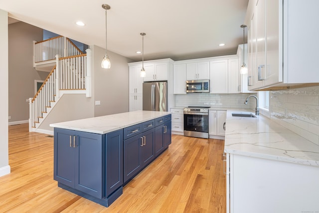 6 Kaatskill Ln, East Lyme, CT 06357 - kitchen with appliances with stainless steel finishes, blue cabinetry, light wood finished floors, backsplash, and recessed lighting