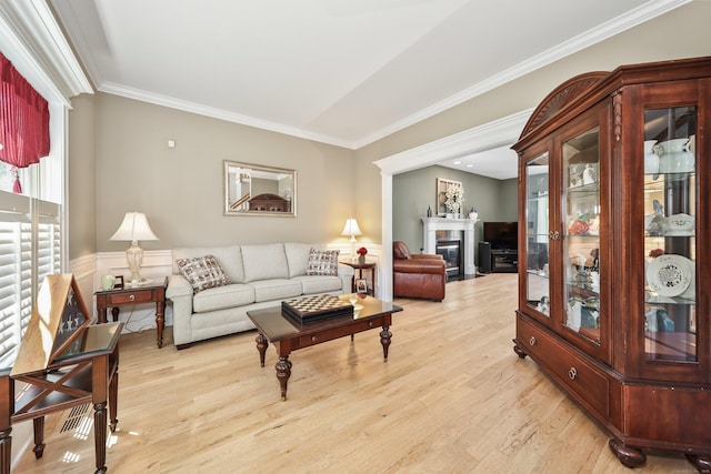 118 Cobblestone Dr, Southington, CT 06479 - living area with light wood-style floors, crown molding, a glass covered fireplace, and wainscoting