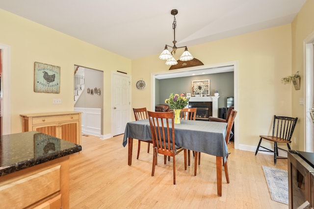 118 Cobblestone Dr, Southington, CT 06479 - dining space featuring light wood-type flooring, a glass covered fireplace, lofted ceiling, and a chandelier