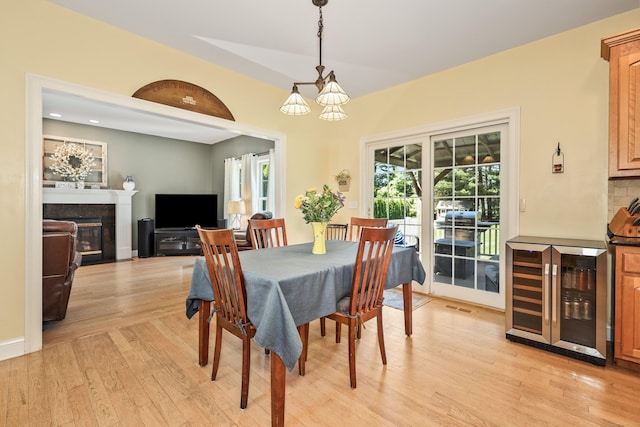 118 Cobblestone Dr, Southington, CT 06479 - dining space featuring beverage cooler, light wood-style floors, a chandelier, a glass covered fireplace, and recessed lighting