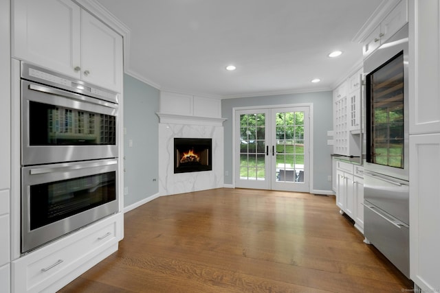 46 Bowman Dr, Greenwich, CT 06831 - kitchen featuring appliances with stainless steel finishes, ornamental molding, dark wood-style floors, white cabinets, and a fireplace