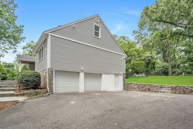 46 Bowman Dr, Greenwich, CT 06831 - view of side of property featuring a garage, a yard, asphalt driveway, and stone siding