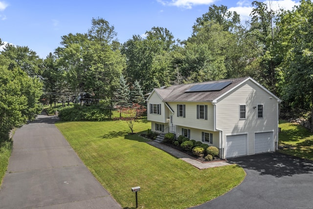 24 Ken Oaks Dr, Danbury, CT 06810 - view of front of home featuring driveway, solar panels, a garage, a front yard, and view of wooded area