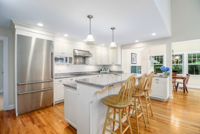 35 Vista Rd, Wilton, CT 06897 - kitchen with stainless steel appliances, under cabinet range hood, white cabinetry, light wood-style flooring, and recessed lighting
