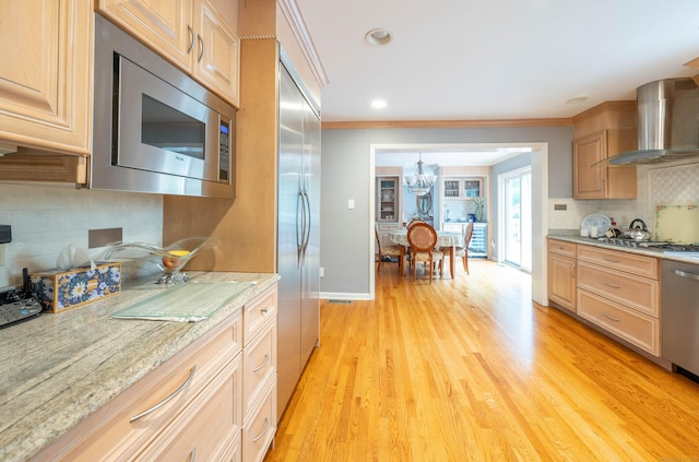 30 Partridge Rd, Stamford, CT 06903 - kitchen featuring built in appliances, wall chimney exhaust hood, backsplash, a chandelier, and light wood-style floors