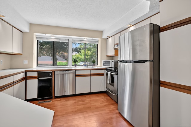 55 Wickhams Fancy Unit 55, Canton, CT 06019 - kitchen featuring appliances with stainless steel finishes, white cabinets, a textured ceiling, light countertops, and light wood-style floors