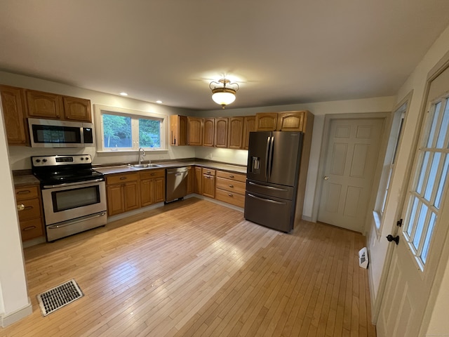 56 N Maple St, Enfield, CT 06082 - kitchen featuring appliances with stainless steel finishes, dark countertops, light wood-style flooring, brown cabinets, and recessed lighting