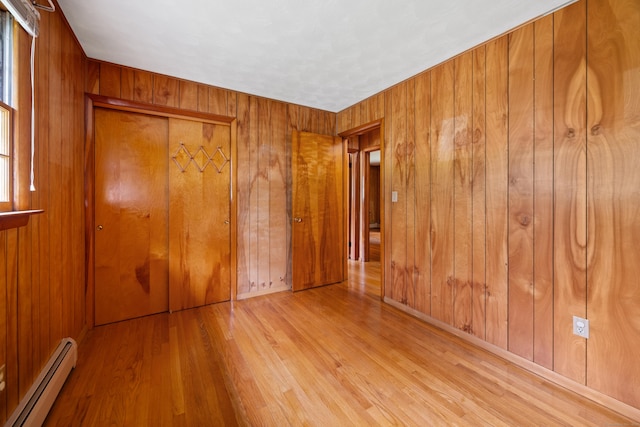 233 Mountain Rd, Cheshire, CT 06410 - unfurnished bedroom featuring baseboard heating, wood finished floors, wooden walls, and a closet