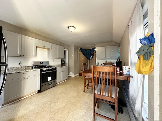 98 Sylvan Ave, New Haven, CT 06519 - kitchen with stainless steel gas range oven, light stone countertops, freestanding refrigerator, and lofted ceiling