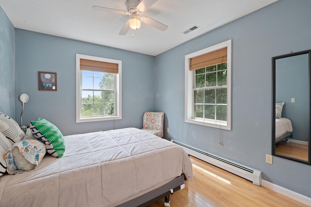 11 Adam Dr, Newington, CT 06111 - bedroom featuring a baseboard heating unit, multiple windows, wood finished floors, and a ceiling fan