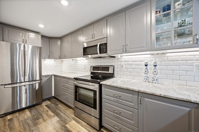 430 Cook Hill Rd, Cheshire, CT 06410 - kitchen with gray cabinetry, appliances with stainless steel finishes, dark wood-style floors, light stone counters, and decorative backsplash