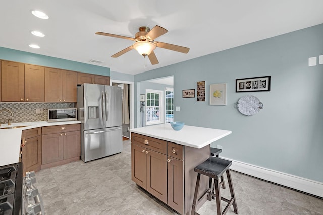 24 Saley Rd, Milford, CT 06460 - kitchen featuring stainless steel appliances, a ceiling fan, a breakfast bar, light countertops, and tasteful backsplash