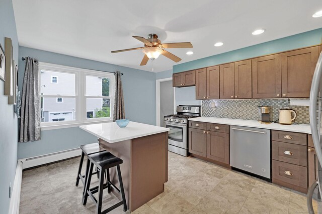 24 Saley Rd, Milford, CT 06460 - kitchen with appliances with stainless steel finishes, a ceiling fan, a kitchen island, a breakfast bar, and light countertops
