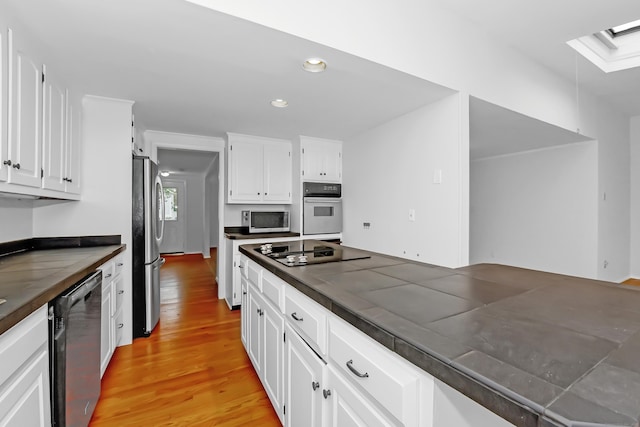 103 Colonial Dr, Fairfield, CT 06824 - kitchen with appliances with stainless steel finishes, dark countertops, white cabinets, light wood-type flooring, and recessed lighting