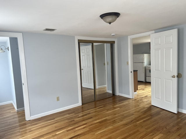 959 First Ave, West Haven, CT 06516 - unfurnished bedroom featuring freestanding refrigerator, wood finished floors, and a closet