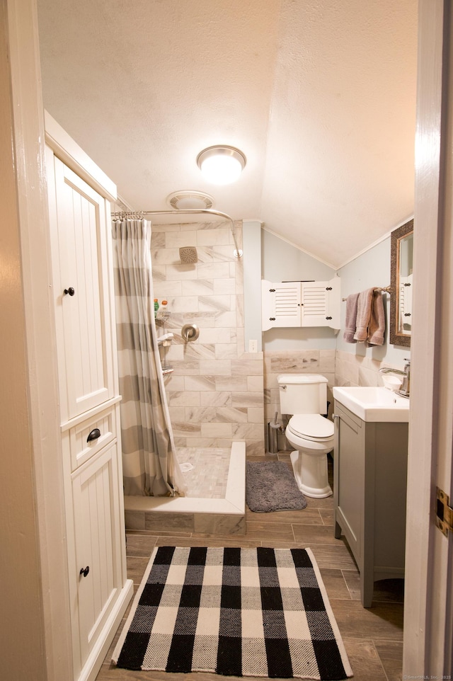 593 Northfield Rd, Watertown, CT 06795 - full bathroom featuring lofted ceiling, vanity, a tile shower, wood finish floors, and tile walls