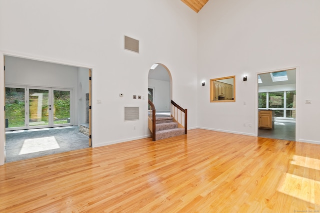 202 High Wood Dr, Glastonbury, CT 06073 - unfurnished living room with high vaulted ceiling, stairway, light wood-style floors, and arched walkways