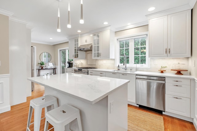 84 Edison Ave, Fairfield, CT 06825 - kitchen with stainless steel appliances, under cabinet range hood, ornamental molding, light wood-style floors, and a kitchen island