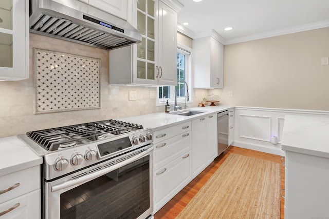 84 Edison Ave, Fairfield, CT 06825 - kitchen with stainless steel appliances, exhaust hood, crown molding, white cabinetry, and tasteful backsplash