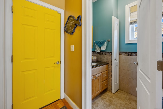 79 Orland St, Milford, CT 06460 - bathroom featuring vanity, tile patterned floors, tile walls, and wainscoting