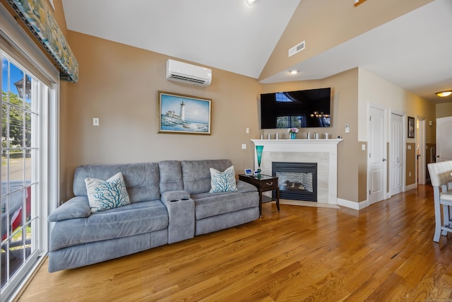 79 Orland St, Milford, CT 06460 - living area with a wall mounted AC, light wood finished floors, lofted ceiling, and a tile fireplace