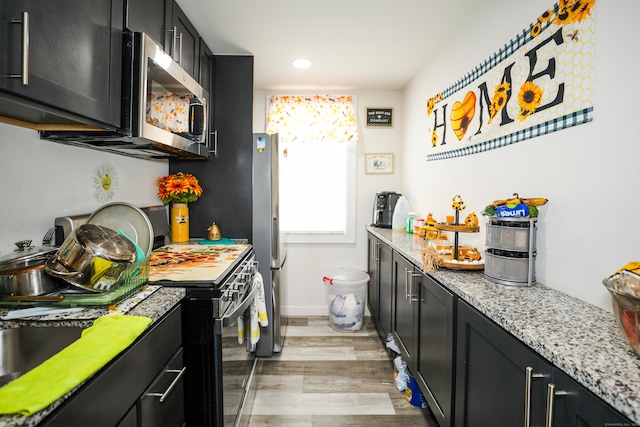 107 Dwight St, New Britain, CT 06051 - kitchen with stainless steel appliances, dark cabinetry, light wood-style flooring, light stone countertops, and recessed lighting
