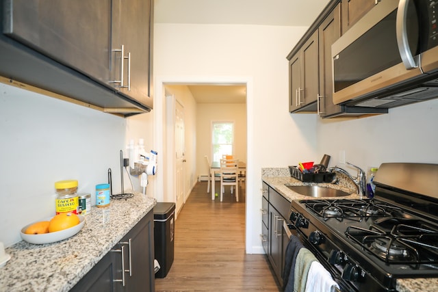 107 Dwight St, New Britain, CT 06051 - kitchen with stainless steel microwave, gas range oven, wood finished floors, and light stone countertops