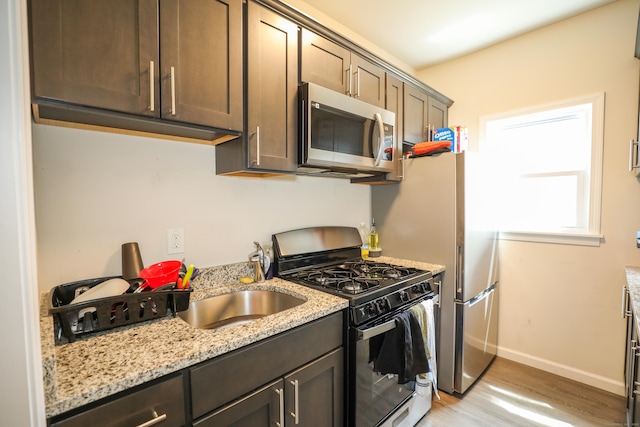 107 Dwight St, New Britain, CT 06051 - kitchen featuring stainless steel microwave, black range with gas stovetop, light wood-style floors, light stone counters, and dark brown cabinetry
