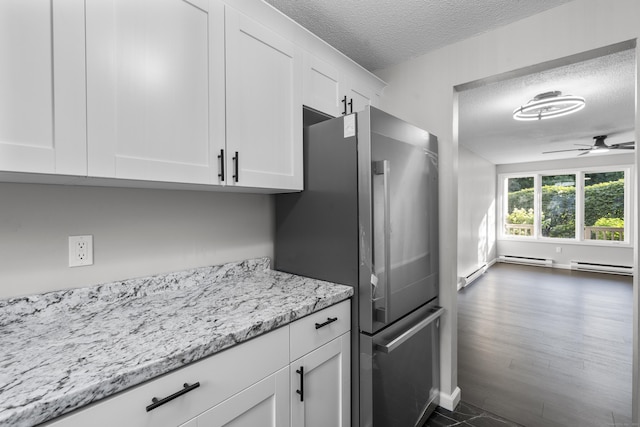 226 E Main St Apt 4, Bristol, CT 06010 - kitchen featuring a textured ceiling, a baseboard radiator, freestanding refrigerator, white cabinetry, and ceiling fan
