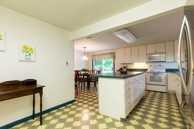 169 Wheeling Rd, Andover, CT 06232 - kitchen with white appliances, dark countertops, light flooring, a center island, and white cabinets