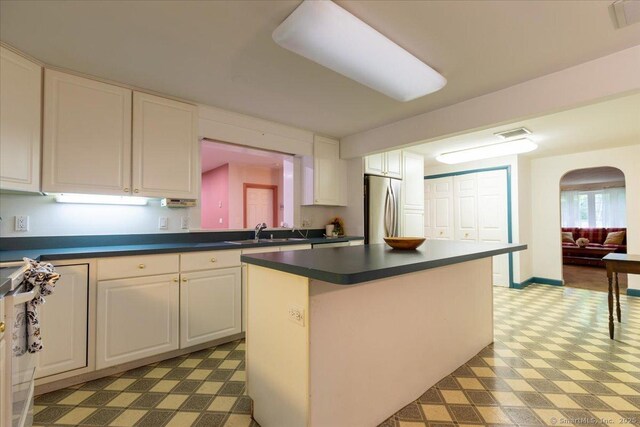 169 Wheeling Rd, Andover, CT 06232 - kitchen with freestanding refrigerator, dark countertops, a kitchen island, white cabinets, and arched walkways