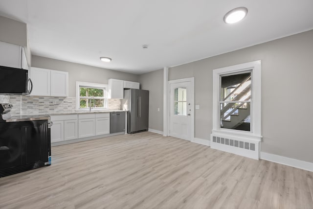 122 Oak St, Naugatuck, CT 06770 - kitchen with radiator, stainless steel appliances, decorative backsplash, light countertops, and light wood-type flooring