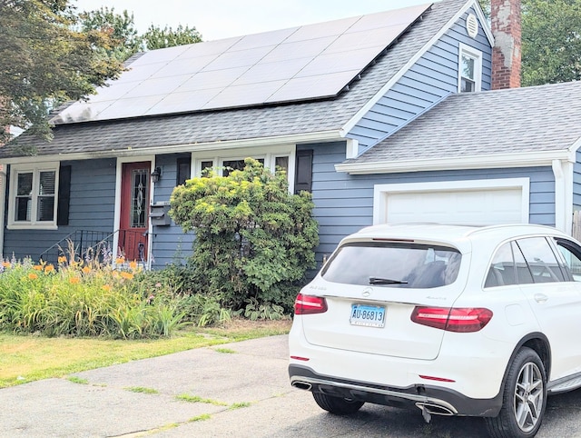 943 Success Ave, Stratford, CT 06614 - view of front facade featuring roof with shingles, a garage, solar panels, and a chimney