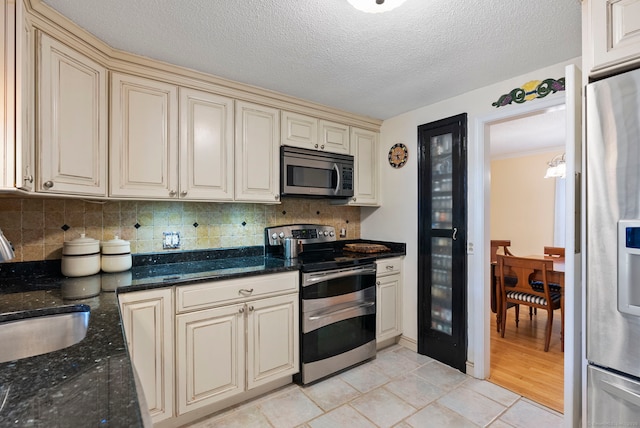 35 Grandview Ter, Wethersfield, CT 06109 - kitchen with stainless steel appliances, cream cabinetry, decorative backsplash, dark stone countertops, and a textured ceiling