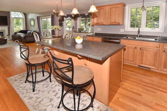 55 Hydrangea Ln, Suffield, CT 06078 - kitchen with light wood-style flooring, a kitchen breakfast bar, a kitchen island, open floor plan, and a glass covered fireplace