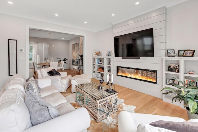 888 Oldfield Rd, Fairfield, CT 06824 - living area featuring wood finished floors, a glass covered fireplace, a chandelier, recessed lighting, and crown molding