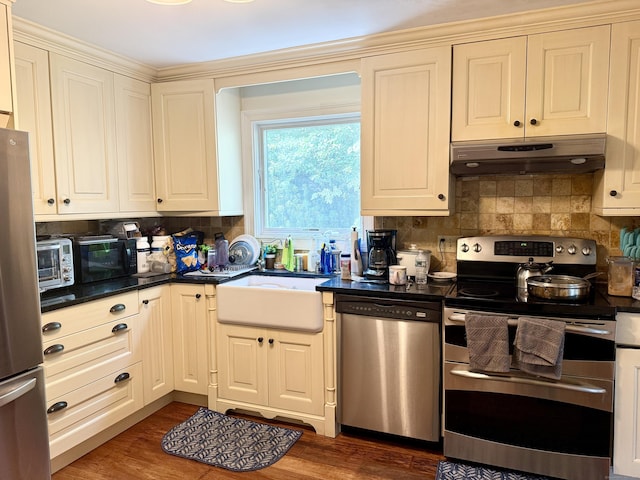 271 Jeniford Rd, Fairfield, CT 06824 - kitchen featuring stainless steel appliances, under cabinet range hood, dark countertops, decorative backsplash, and dark wood finished floors