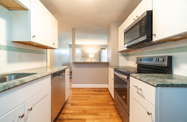635 Ruth St, Bridgeport, CT 06606 - kitchen with stainless steel appliances, light wood-style flooring, decorative backsplash, white cabinetry, and stone countertops