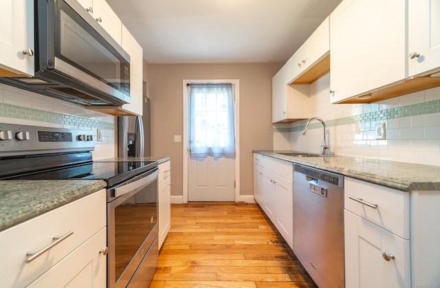 635 Ruth St, Bridgeport, CT 06606 - kitchen featuring appliances with stainless steel finishes, light wood-style floors, backsplash, and white cabinetry