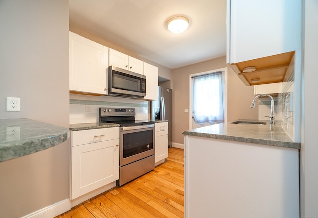 635 Ruth St, Bridgeport, CT 06606 - kitchen with stainless steel appliances, decorative backsplash, light wood finished floors, white cabinets, and stone countertops