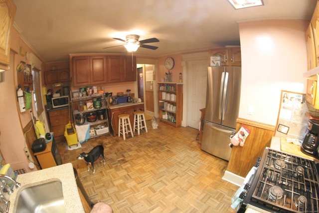 375 Baldwin St, Waterbury, CT 06706 - kitchen featuring stainless steel appliances, a ceiling fan, brown cabinetry, a wainscoted wall, and crown molding