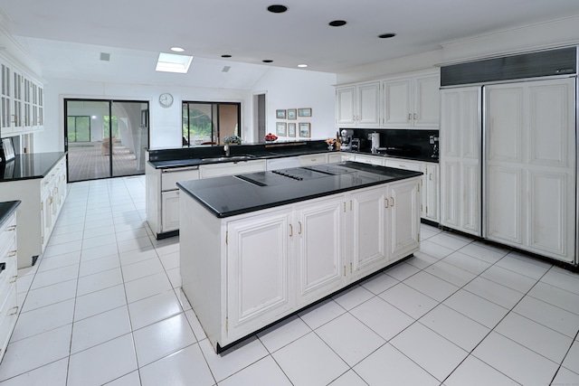 3853 Congress St, Fairfield, CT 06824 - kitchen with paneled refrigerator, a peninsula, dark countertops, a kitchen island, and white cabinetry