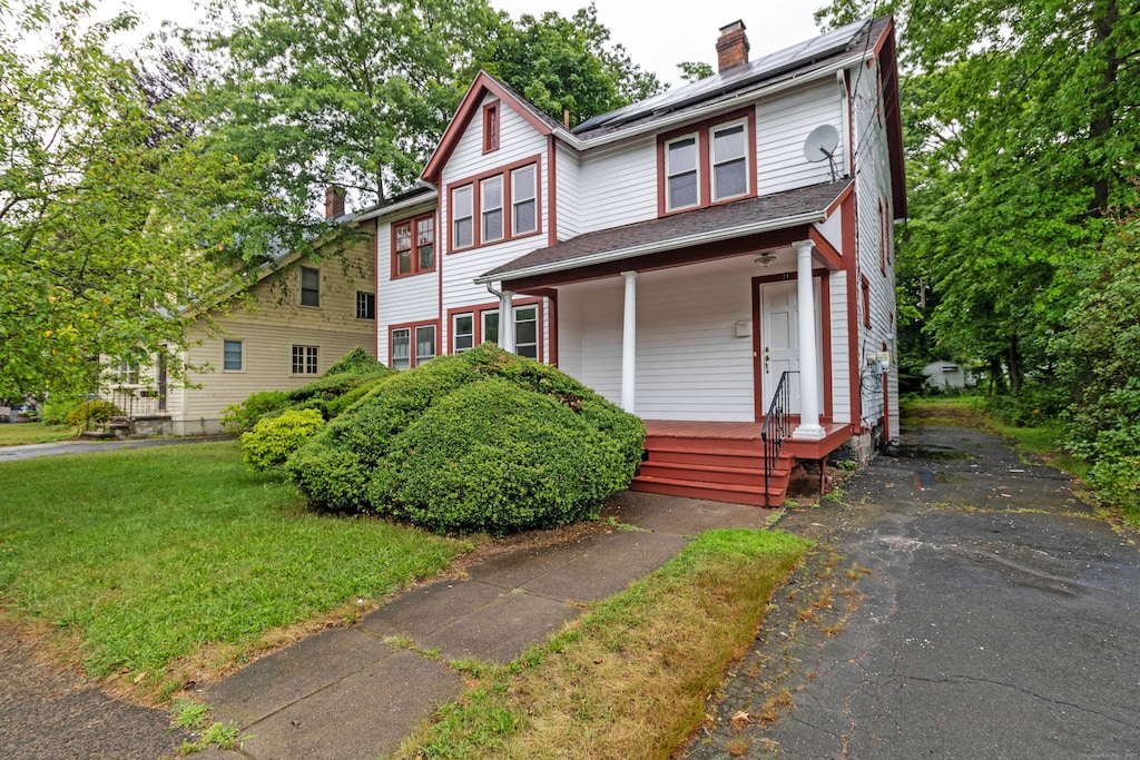 21 Richmond Ave, New Haven, CT 06515 - view of front facade featuring covered porch, a chimney, solar panels, and a front yard