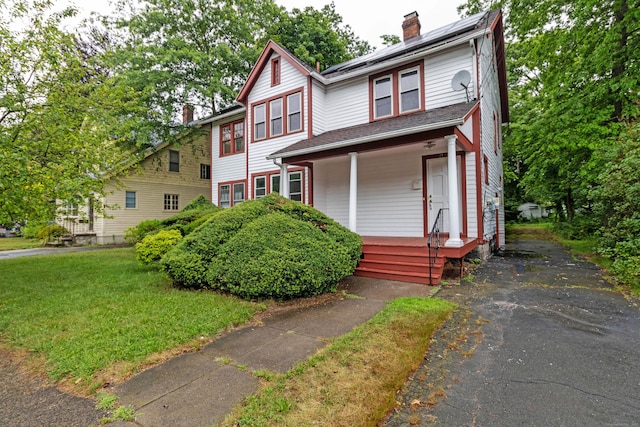 21 Richmond Ave, New Haven, CT 06515 - view of front facade featuring covered porch, a chimney, solar panels, and a front yard