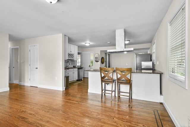 198 Macon Dr, Bridgeport, CT 06606 - kitchen with island range hood, a peninsula, stainless steel appliances, wood finished floors, and white cabinetry