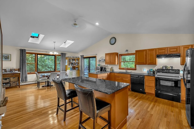 41 Fog Plain Rd, Waterford, CT 06385 - kitchen with black appliances, a skylight, under cabinet range hood, a breakfast bar area, and light wood-type flooring