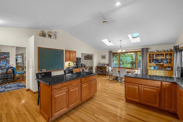 41 Fog Plain Rd, Waterford, CT 06385 - kitchen with a skylight, lofted ceiling, light wood-type flooring, brown cabinetry, and dark stone counters