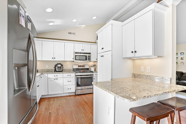 76 Valley View Rd, Norwalk, CT 06851 - kitchen featuring stainless steel appliances, a peninsula, lofted ceiling, light wood-type flooring, and white cabinetry