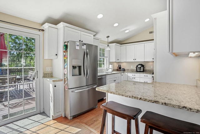 76 Valley View Rd, Norwalk, CT 06851 - kitchen featuring stainless steel appliances, a breakfast bar area, light wood finished floors, white cabinets, and vaulted ceiling