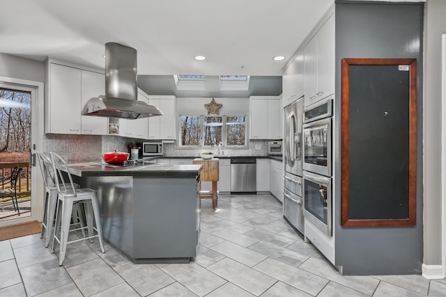 80 Norton Rd, Easton, CT 06612 - kitchen featuring island range hood, stainless steel appliances, a peninsula, dark countertops, and a kitchen bar